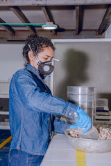 Fototapeta na wymiar Female industrial worker with protective mask and blue latex gloves, scooping out rock with a small shovel, in a geological testing laboratory