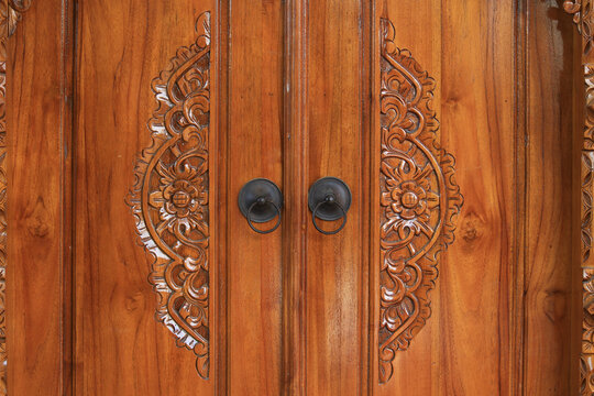 unique, vintage, and artistic doorknobs in ethnic buildings. The door is made of wood and carved with typical Indonesian carvings.