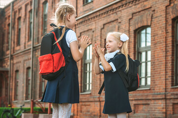 Two great Schoolgirls give each other five. First day of study. Concept on the topic Back to School.