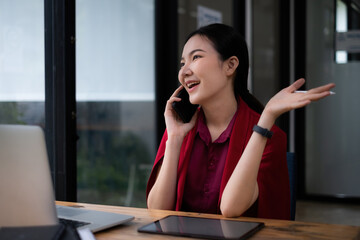Photo of gorgeous secretary talking with customer by cell phone at office. she sitting at the wooden desk.