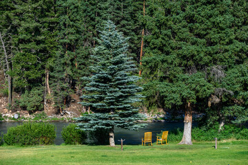 Pair of wooden rocking chairs on a green lawn at the edge of the Gallatin River
