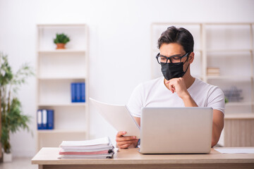 Young male student employee working at workplace during pandemic