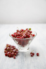 Frozen red currants in a glass vase on a white wooden table. Close-up.