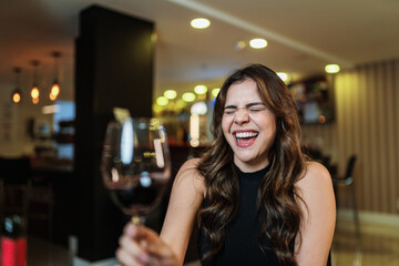 Young Latin woman with a glass of red wine on the bar