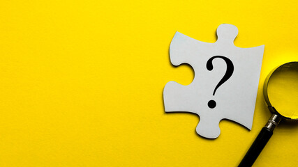 Questions symbol on a white piece of jigsaw puzzle on a yellow background with copy space.