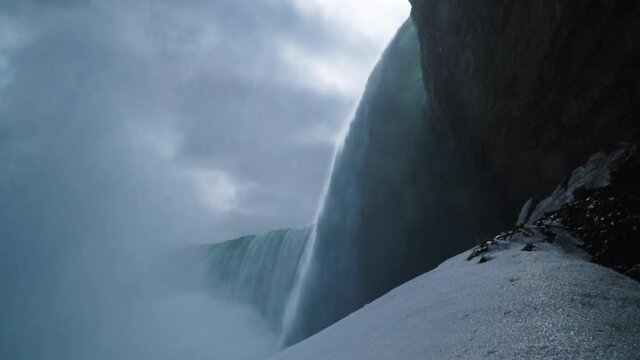 Low angle wide shot waterfall overhang undercut at Niagara Falls slow motion