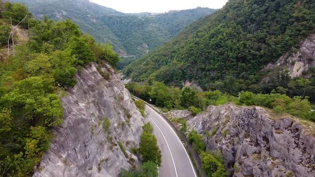 Cinematic drone shot over road and river and nature in italian mountains