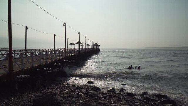 Tourists Swim in the Ocean Next to a Pier at Huanchaco, Trujillo, La Libertad, Peru