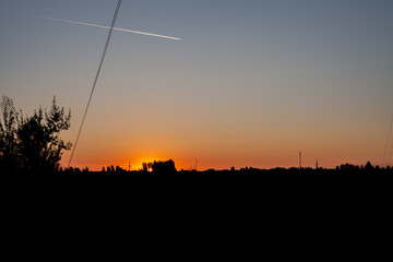 Naklejka premium trail of a flying plane in the morning sky at dawn