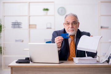 Old male employee holding credit card in the office