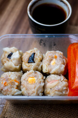 close up picture of steamed dimsum, with sambals, and blurry a cup of coffee