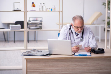 Obraz premium Old male doctor working in the clinic