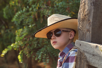 portrait of a boy in a cowboy hat and sunglasses in nature