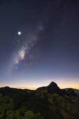 Milky Way galaxy with stars at night in mountain forest and sunrise.