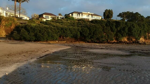 low flying drone footage of Beach at low tide with reflections in still water.