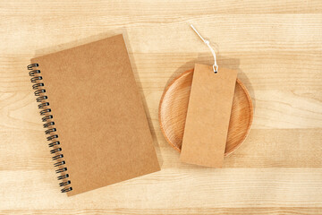 Notepad and blank rustic label on wooden work desk.