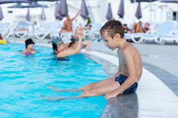Fototapeta premium The boy on the side of the pool is smiling. The open air swimming pool.