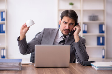 Young male employee drinking coffee during break