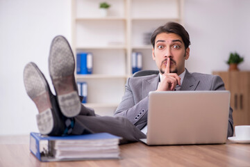 Young attractive male employee sitting at workplace