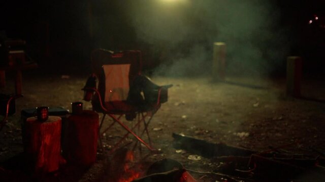 Burning firewood at night campsite with camping equipment in background