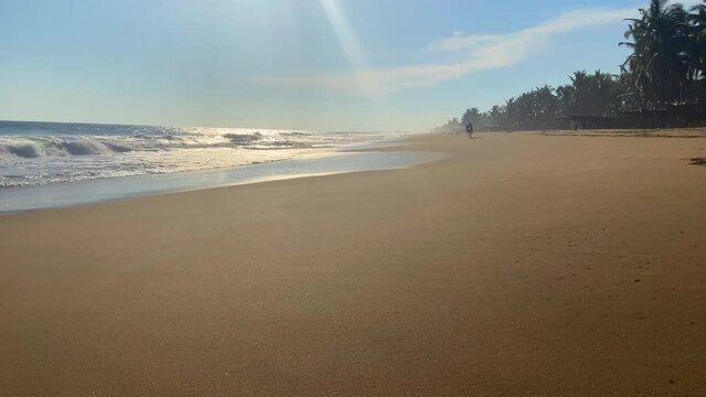 Paisaje de playa en la tarde con caballo y jinete paseando al fondo. Pie de la Cuesta, Acapulco, México.