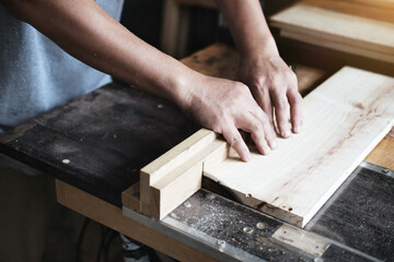 Woodworking practitioners use saw blades to cut wood pieces to assemble and build wooden tables for their clients.