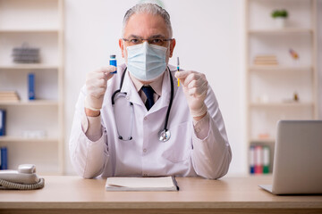 Old male doctor in vaccination concept