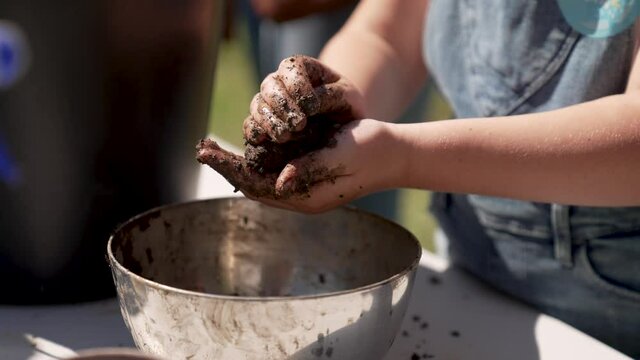 Close up of person making a seed bomb above an iron bowl. Made to plant in forest and infertile areas for greenery intentions.