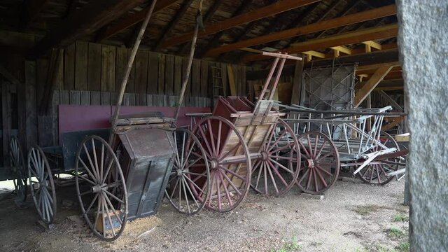 Pan left to to reveal 19th century Shaker Amish wagons in a barn