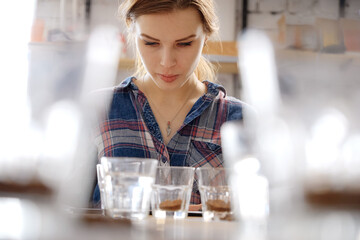 Pretty female barista surrounded with coffee cups