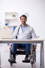 Young male doctor in wheel-chair working in the clinic