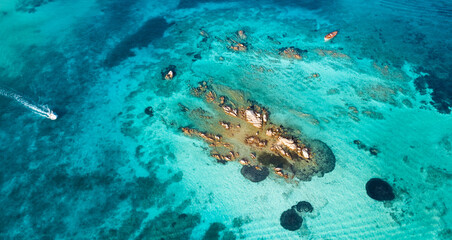 View from above, stunning aerial view of a boat sailing on a crystal clear, turquoise water. Giardinelli island, La Maddalena Archipelago, Sardinia, Italy.