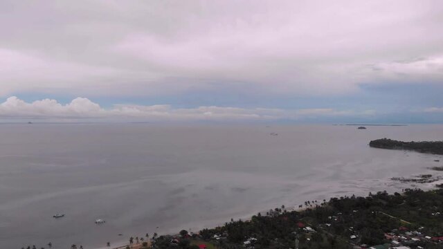 Aerial shot of the province of Cebu, Daanbantayan. Visible shoreline, landscape and seascape. Shot in the afternoon with clouds and clear horizon. Below is the green and open fields and houses.