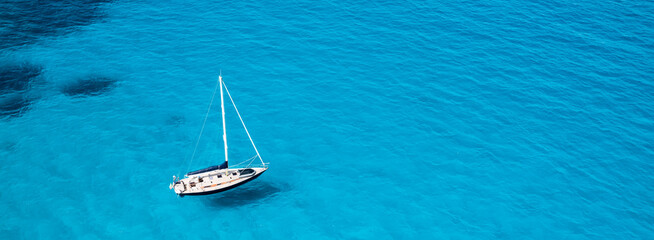 View from above, stunning aerial view of a sailboat floating on a turquoise, crystal clear water...