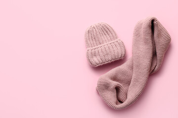 Warm hat and scarf on color background