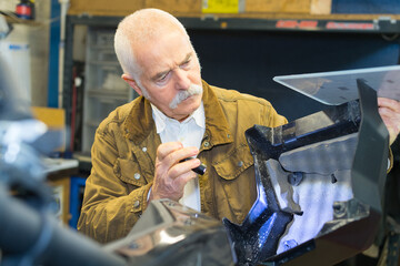 senior man inspecting motorbike