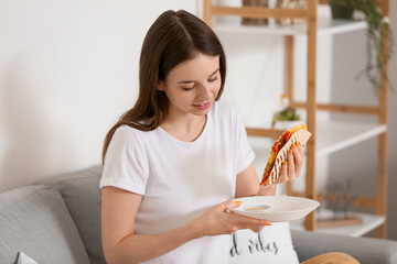 Obraz na płótnie Canvas Beautiful young woman eating tasty quesadilla at home