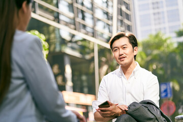 two asian business associates talking outdoors