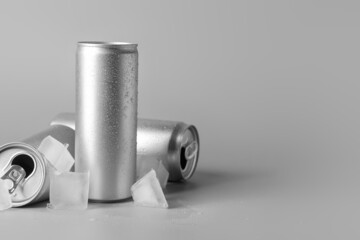Cans of soda and ice cubes on grey background
