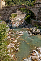 The ancient Pont Saint Martin bridge, in the historic center of the homonymous village, on a sunny day, Aosta Valley, Italy