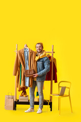 Male stylist with clothes on color background