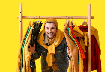 Male stylist with clothes on color background