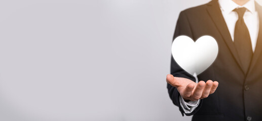Male hand holding heart , like icon on blue background. Kindness, charity, pure love and compassion concept.Banner with copy space