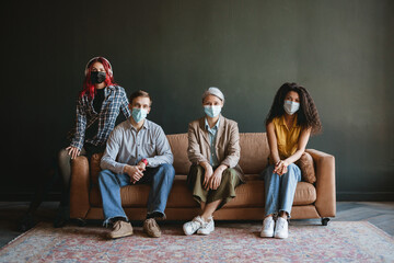 Man and women in face mask looking at camera while sitting on couch