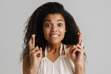 Black woman holding fingers crossed for good luck and looking at camera