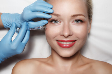 Attractive woman at plastic surgery with syringe in her face