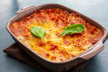 Baking dish with tasty vegetable lasagna on dark background