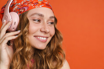 Young ginger woman wearing bandana listening music with headphones