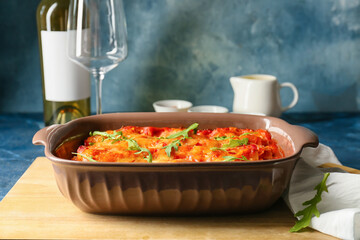 Baking dish with tasty tomato lasagna on color background