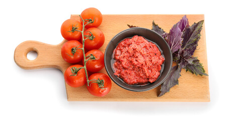 Wooden board with bowl of tasty pesto sauce, fresh basil and tomatoes on white background